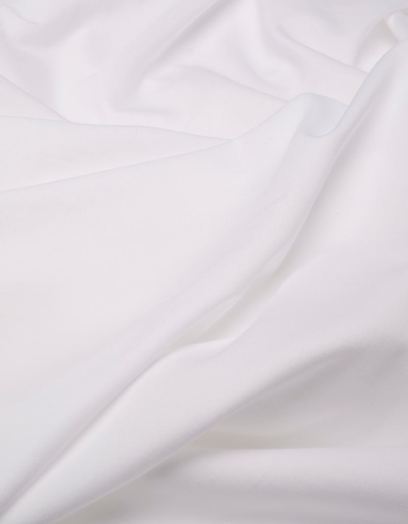 A close-up of the Cozy Earth Soft-Wash Cotton Flat Sheet shows white fabric with soft folds and gentle creases, creating a smooth, flowing texture.