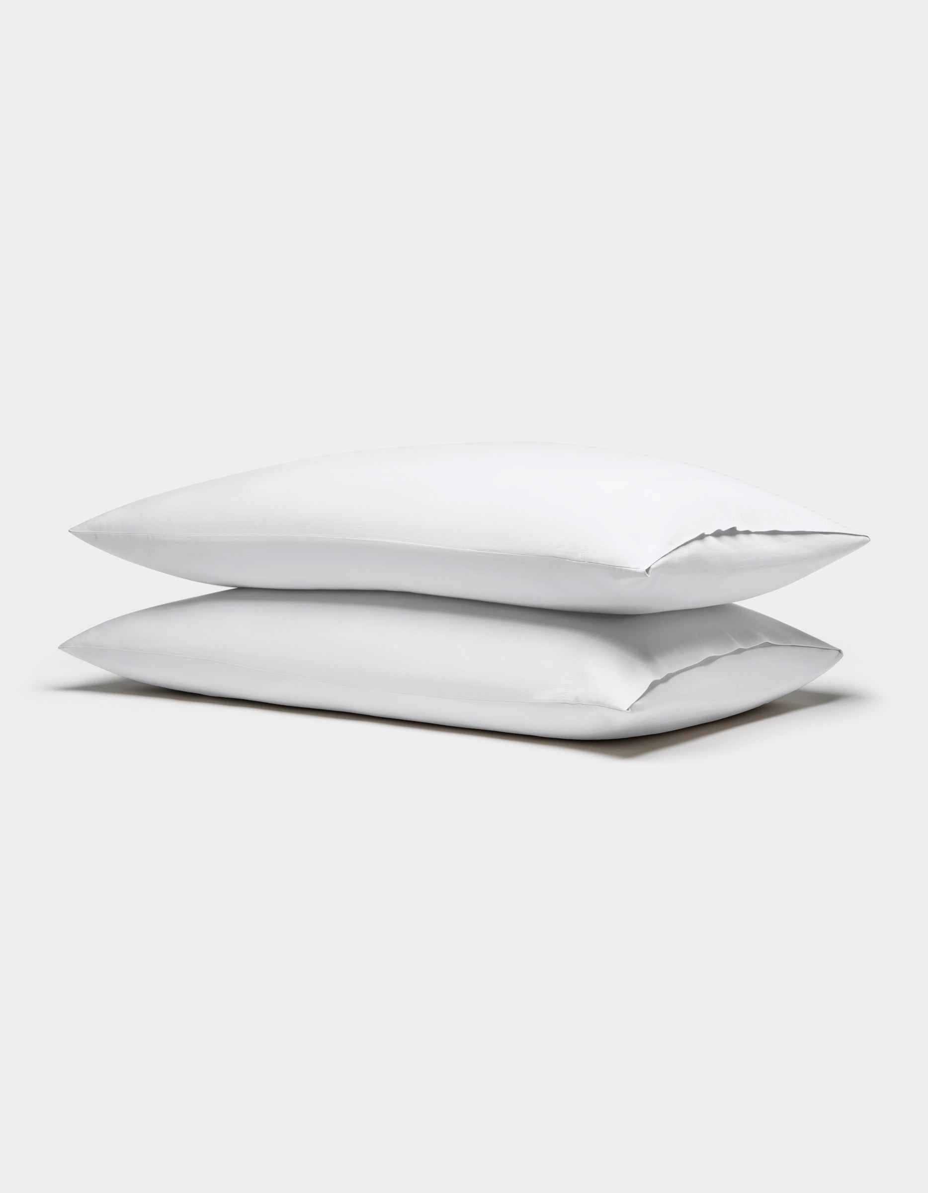 Two Cozy Earth Soft-Wash Cotton Pillowcases in white are stacked against a plain light gray background.|Color:White