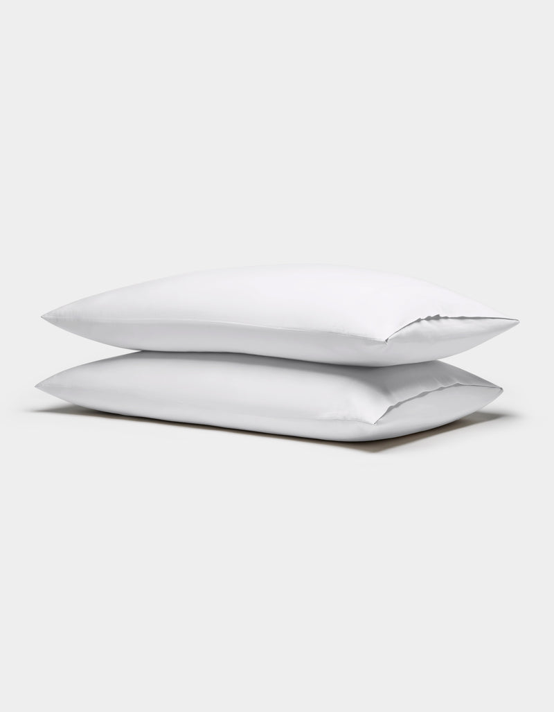 Two Cozy Earth Soft-Wash Cotton Pillowcases in white are stacked against a plain light gray background.