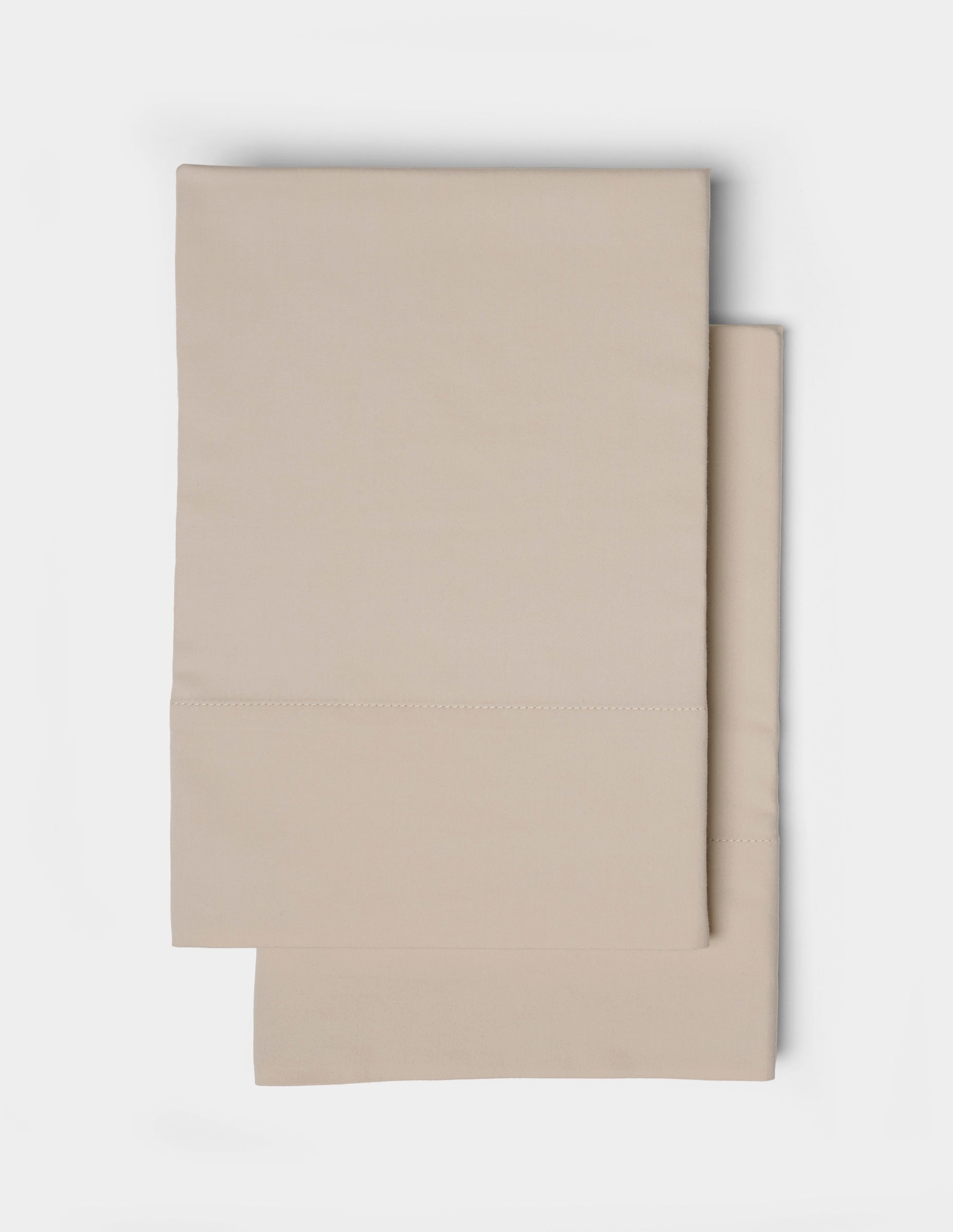 A pair of beige pillowcases from the Cozy Earth Soft-Wash Cotton Sheet Set, featuring a simple stitched border, neatly folded and displayed on a white background.
