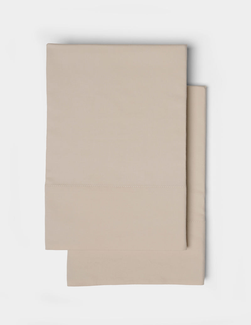 A pair of beige pillowcases from the Cozy Earth Soft-Wash Cotton Sheet Set, featuring a simple stitched border, neatly folded and displayed on a white background.
