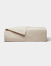The Cozy Earth Soft-Wash Cotton Quilt, featuring a smooth quilted design in light beige, is neatly folded against a plain white background.|Color:Driftwood