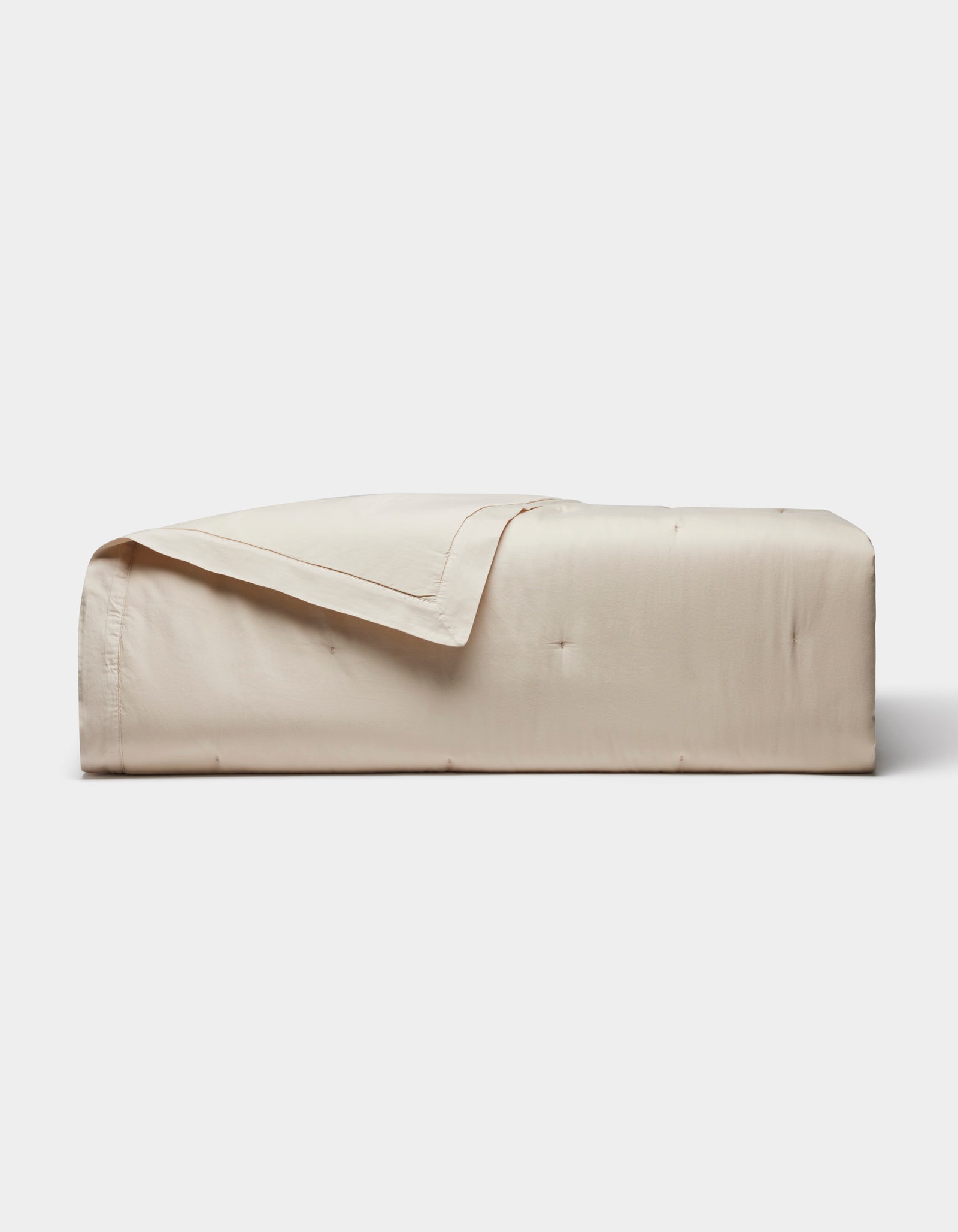 The Cozy Earth Soft-Wash Cotton Quilt, featuring a smooth quilted design in light beige, is neatly folded against a plain white background.