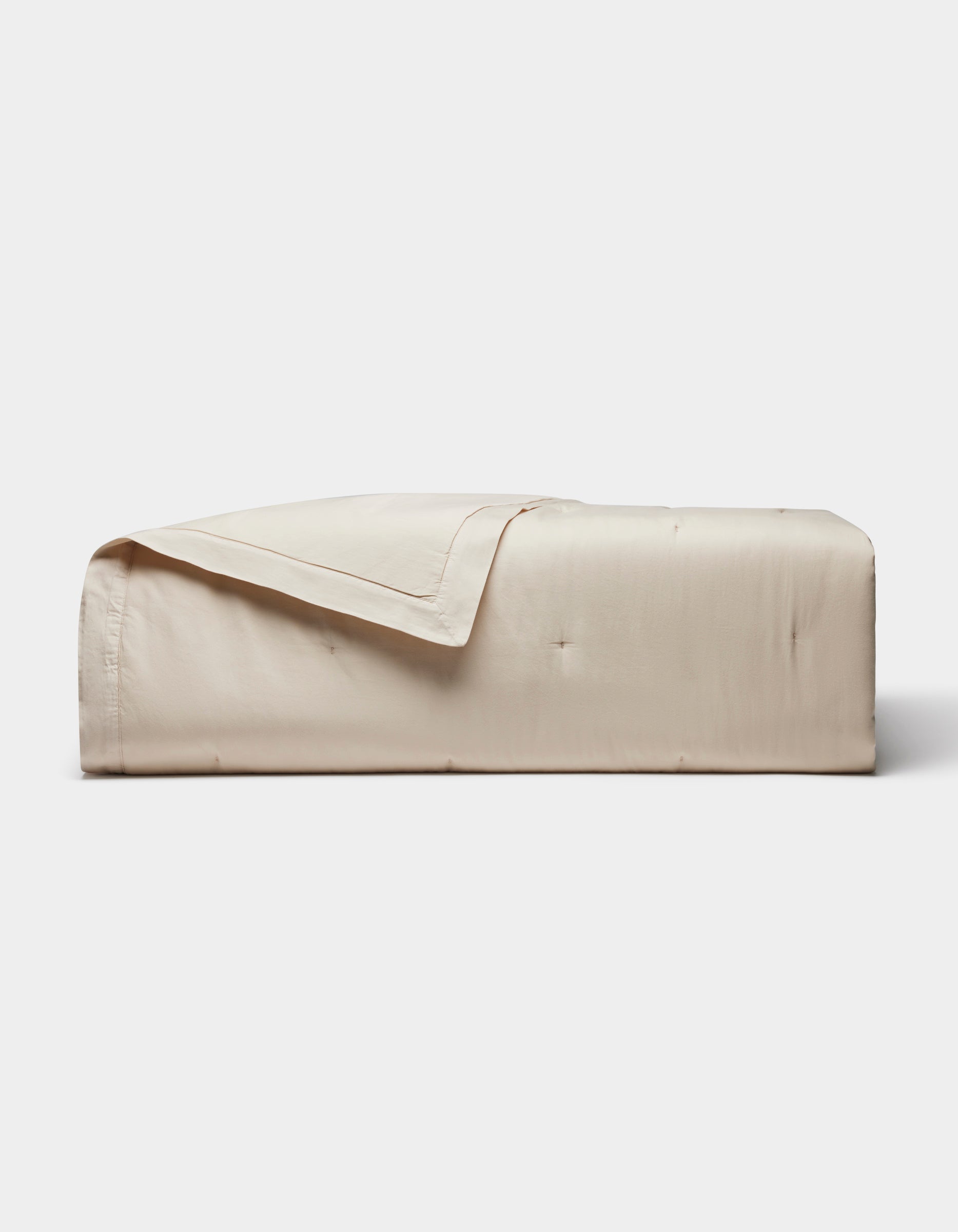 The Cozy Earth Soft-Wash Cotton Quilt, featuring a smooth quilted design in light beige, is neatly folded against a plain white background.|Color:Driftwood