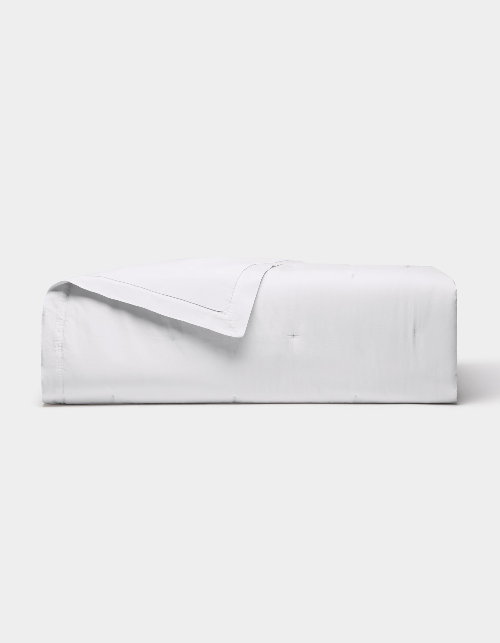 The Cozy Earth Soft-Wash Cotton Quilt is neatly folded with one corner turned down, showcased against a plain light gray background.