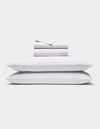 The Cozy Earth Soft-Wash Cotton Sheet Set in white, featuring a flat sheet, fitted sheet, and two pillowcases, is shown neatly stacked against a plain white background.|Color:White