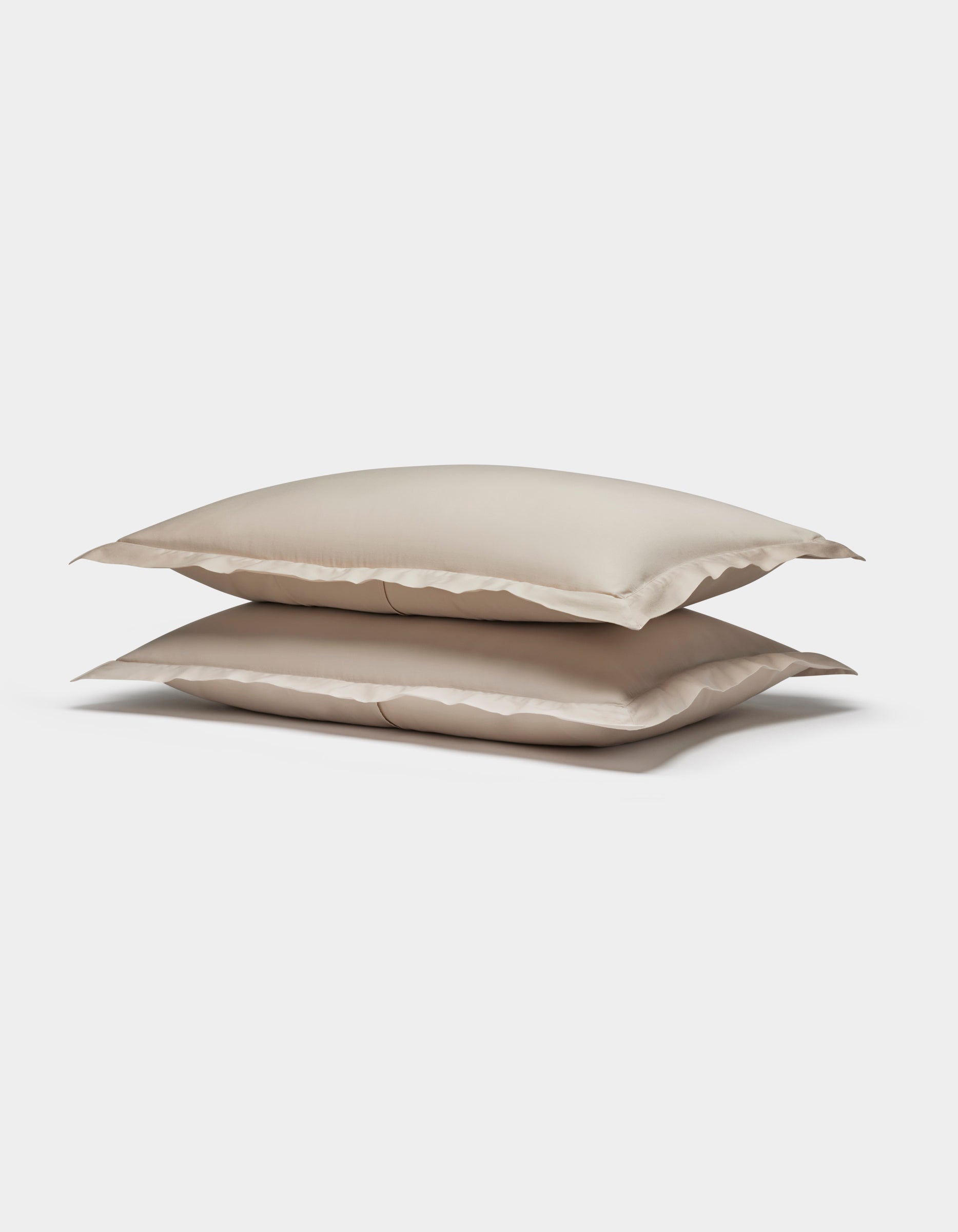 Two Soft-Wash Cotton Shams by Cozy Earth, in beige, are stacked neatly together against a plain white background.|Color:Driftwood