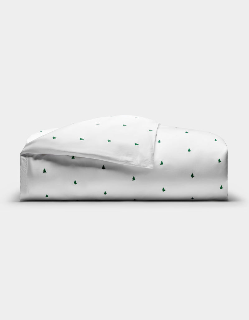 The Cozy Earth Bamboo Duvet Cover, featuring a minimal pattern of small green Christmas trees, is neatly folded on a plain white background.