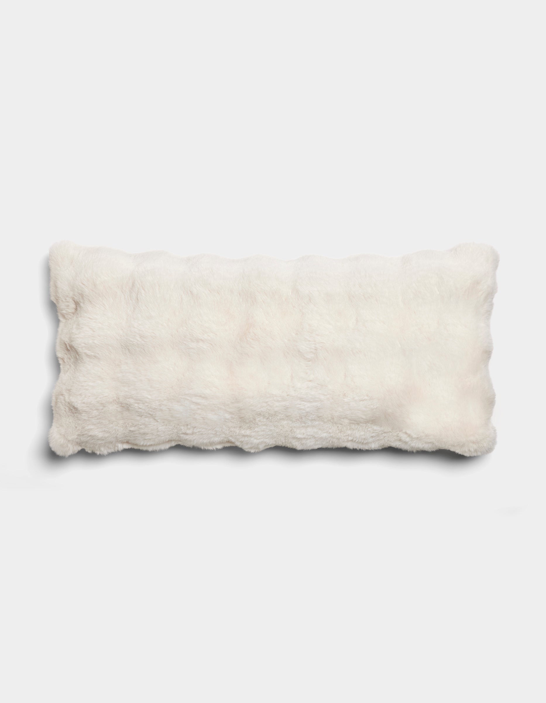 The Bubble Cuddle Pillow by Cozy Earth is a rectangular, fluffy white pillow with a soft, furry texture, displayed on a plain light gray background.