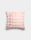 The Bubble Cuddle Pillow by Cozy Earth is a square, pale pink plush pillow with a soft, fuzzy texture and subtle horizontal ridges, shown against a plain light gray background.|Color:Blossom |Size:20" x 20"