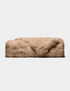 The Double Bubble Cuddle Blanket by Cozy Earth, a rectangular beige faux fur throw, rests on a plain white background with one corner of the plush fur softly folded over the top.|Color:Brandy