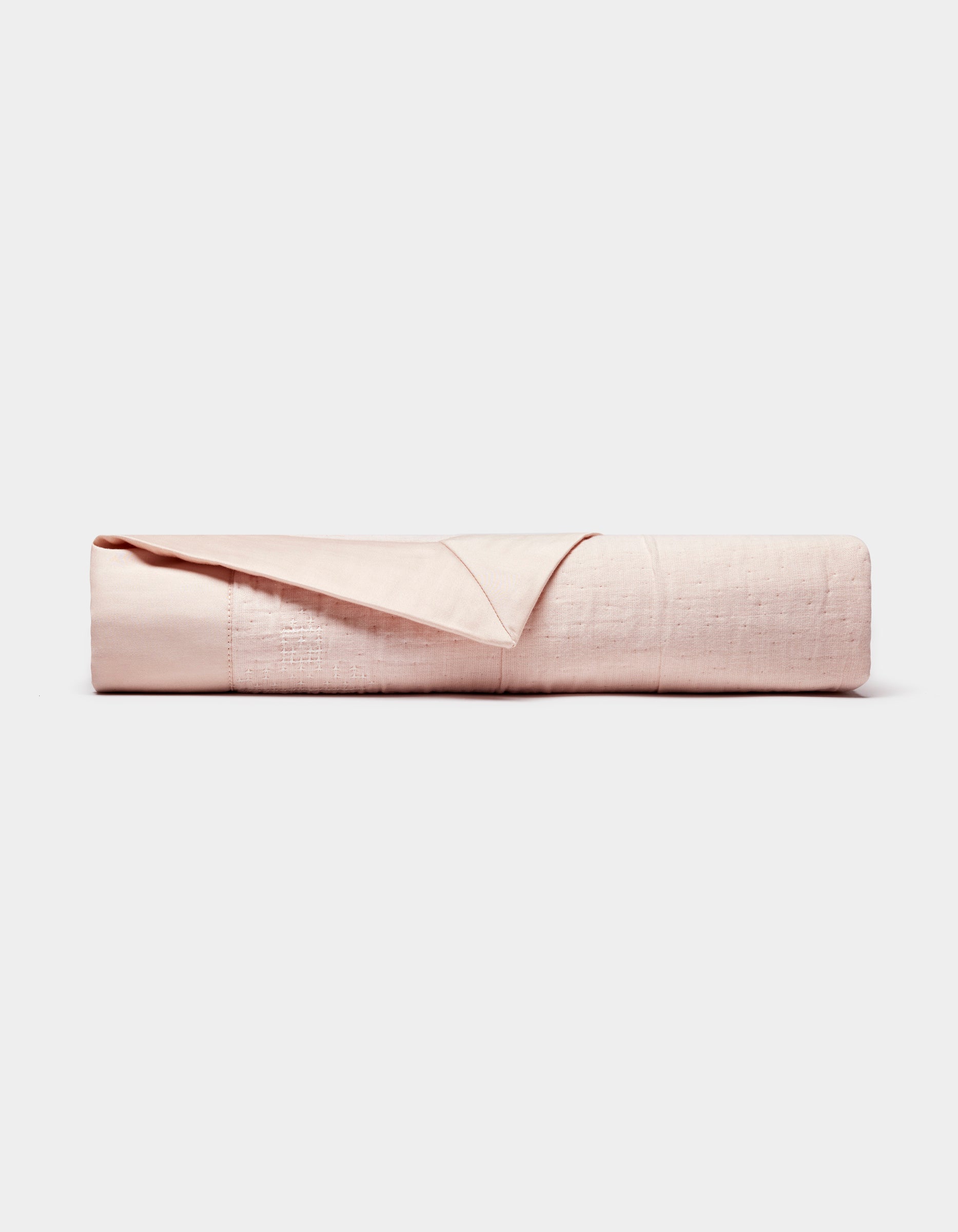 The Cozy Earth Little Bee Matelasse Baby Blanket is neatly folded, showcasing its light pink, textured surface against a plain white background.|Color:Petal