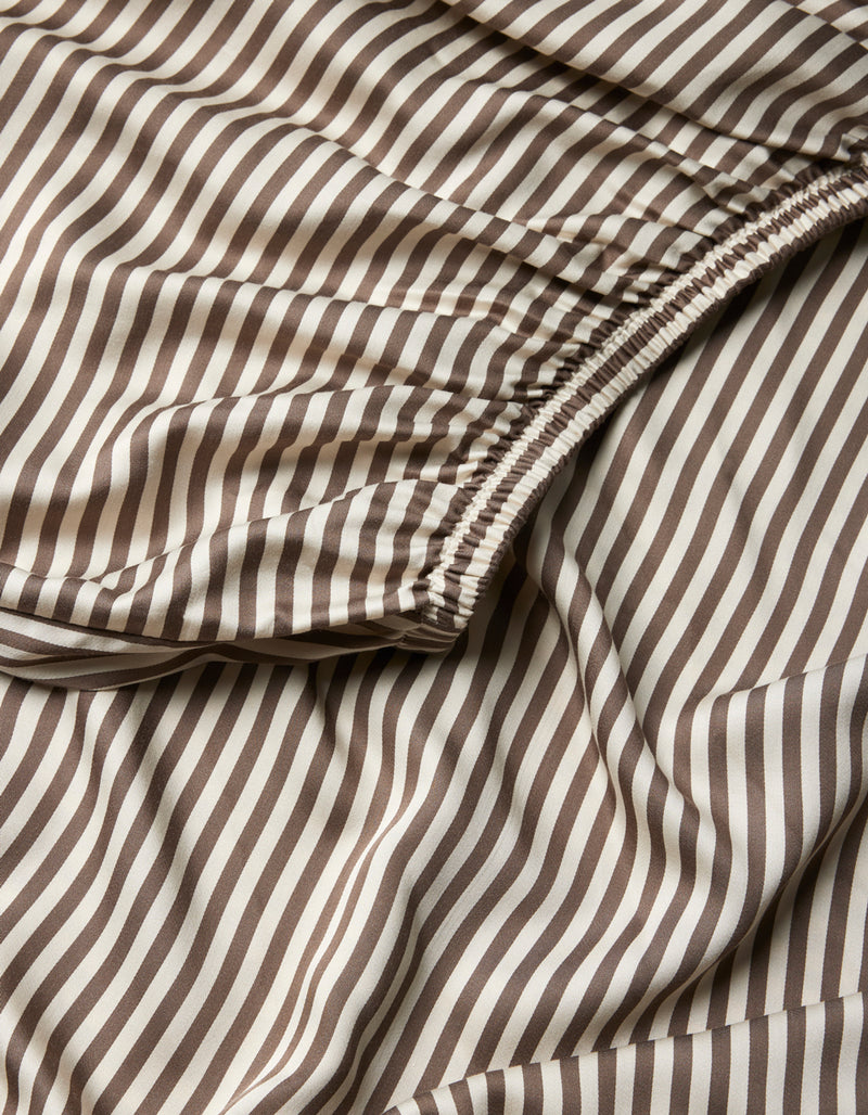 Close-up of Cozy Earth Bamboo Fitted Sheet, showcasing brown and white vertical stripes with a gathered, elasticized section and a smooth, flowing texture.