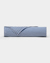 A Bamboo Sheet Set by Cozy Earth in navy blue and white stripes lies rolled on a plain white surface, with one corner partially unfolded to reveal the underside of the fabric.|Color:Classic Stripe in Pacific