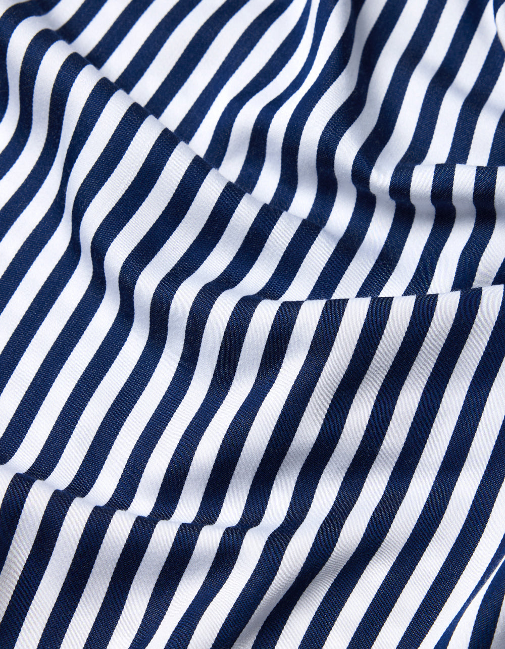 Close-up of Cozy Earth’s Bamboo Sheet Set fabric, featuring navy blue and white vertical stripes. The material is slightly wrinkled, adding gentle folds and waves to the striped pattern.