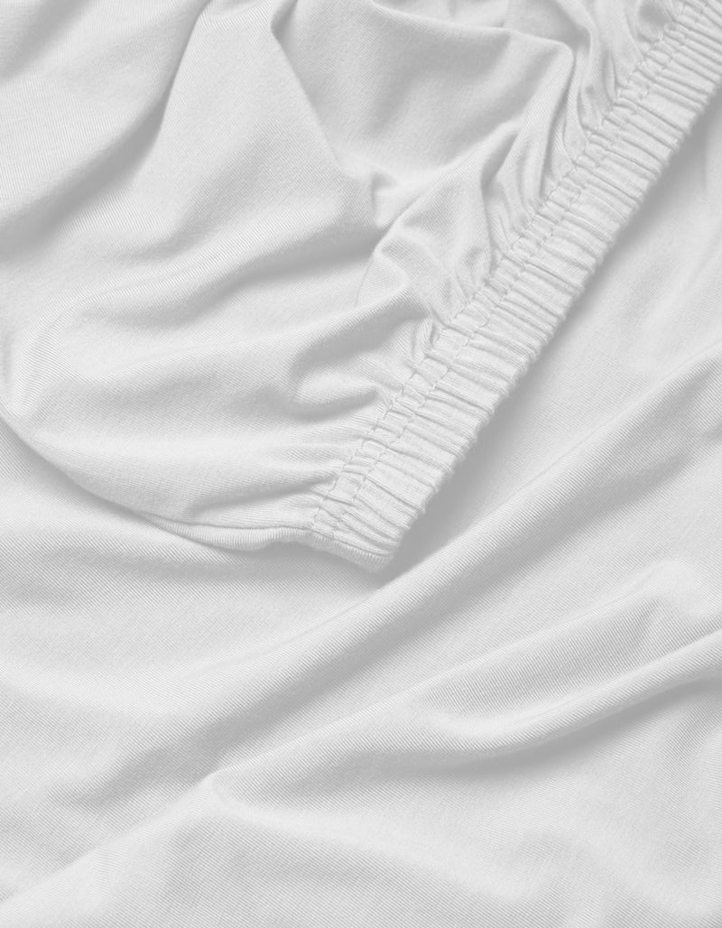 A close-up of the Cozy Earth Bamboo Jersey Fitted Sheet highlights its elasticized edge, smooth surface, and gentle folds for a soft, snug fit.