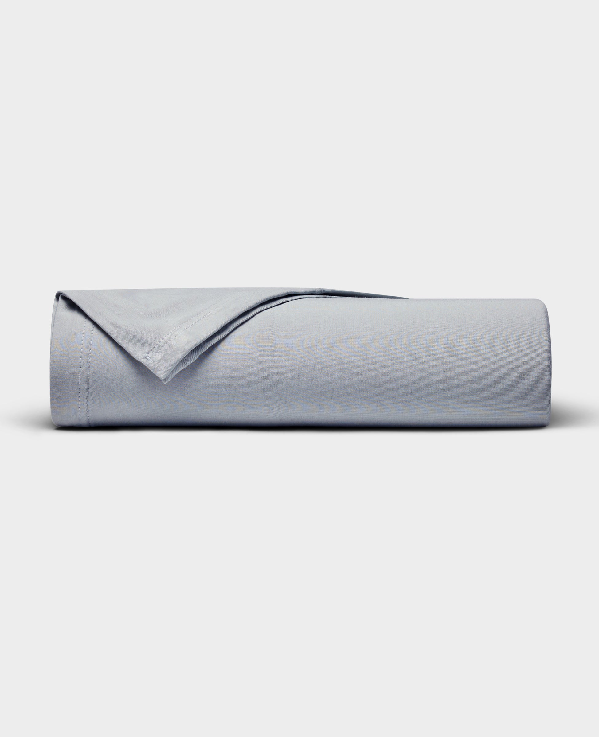 The Cozy Earth Bamboo Jersey Flat Sheet is neatly rolled with a folded edge and displayed on a plain white background.|Color:Shore
