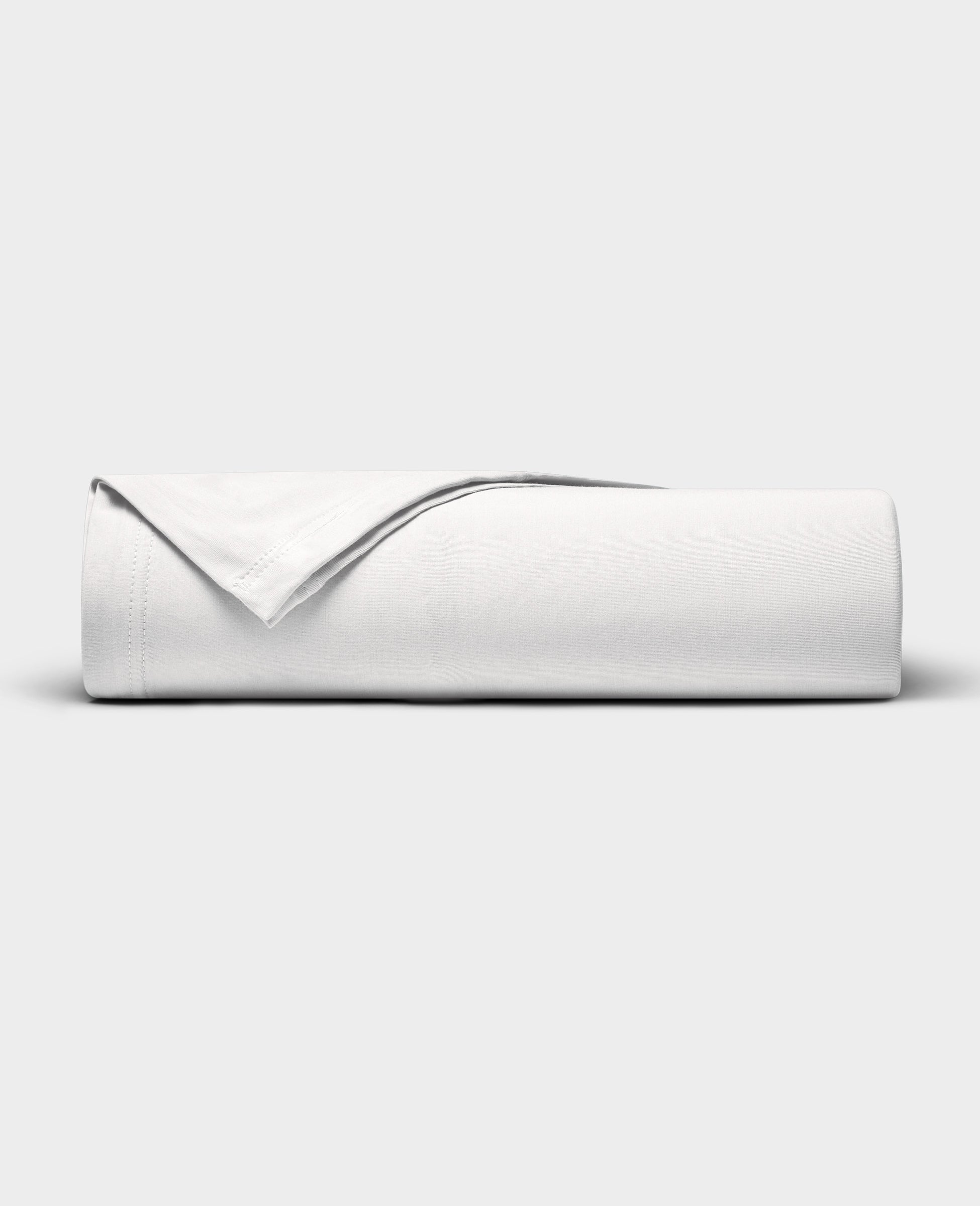 The Cozy Earth Bamboo Jersey Flat Sheet is neatly folded with a corner turned back, showcased against a plain light gray background.|Color:White