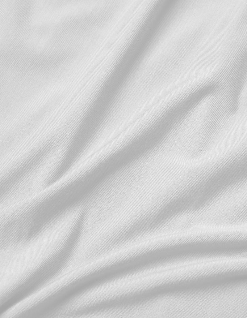A close-up of the Cozy Earth Bamboo Jersey Flat Sheet shows its smooth white fabric with soft folds, gentle creases, and subtle shadows, highlighting the luxurious texture.