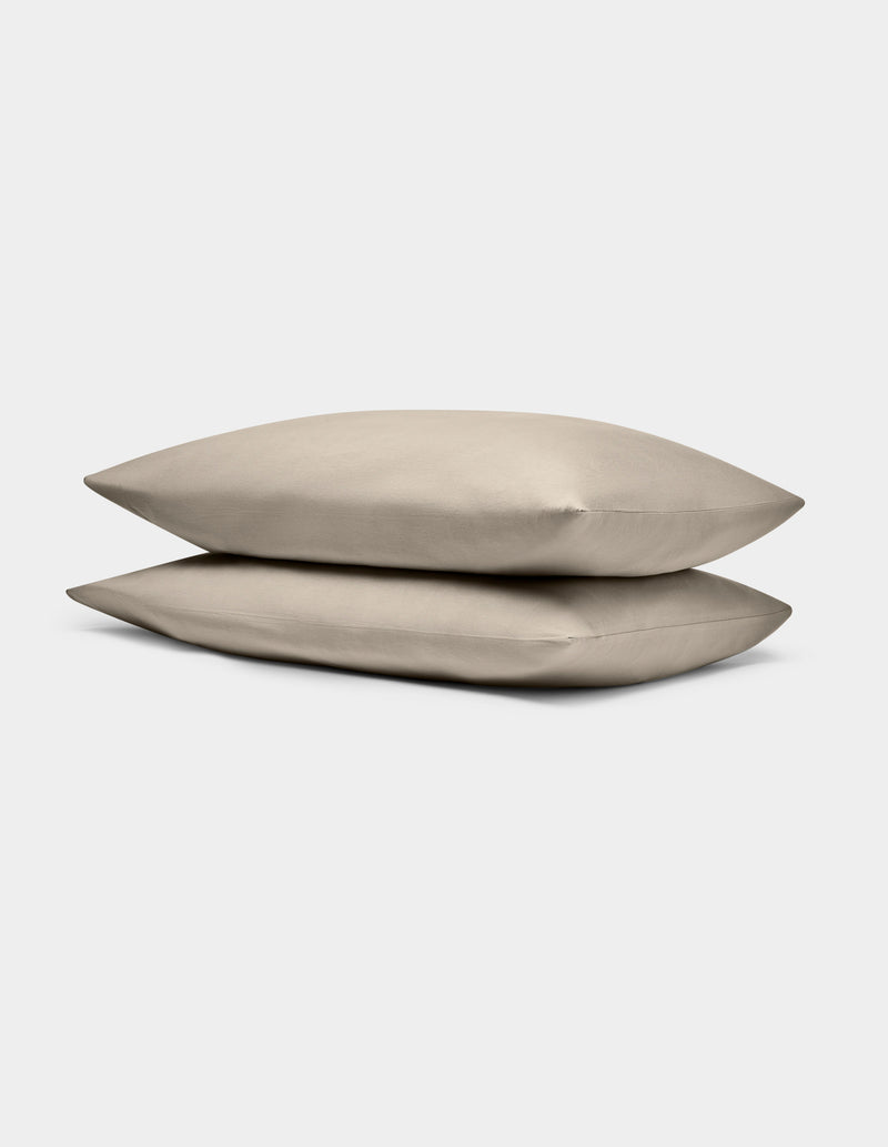 Two Cozy Earth Bamboo Jersey Pillowcases in beige are stacked atop one another against a plain white background.