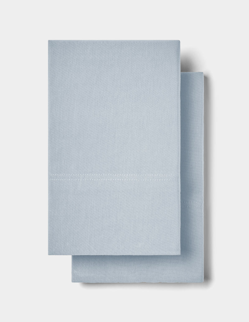 Two neatly folded Cozy Earth Bamboo Jersey Pillowcases in light blue are stacked on top of each other against a plain white background.