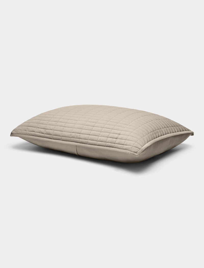 The Bamboo Jersey Quilted Shams by Cozy Earth are beige, rectangular pillows featuring a quilted pattern, displayed against a plain white background.