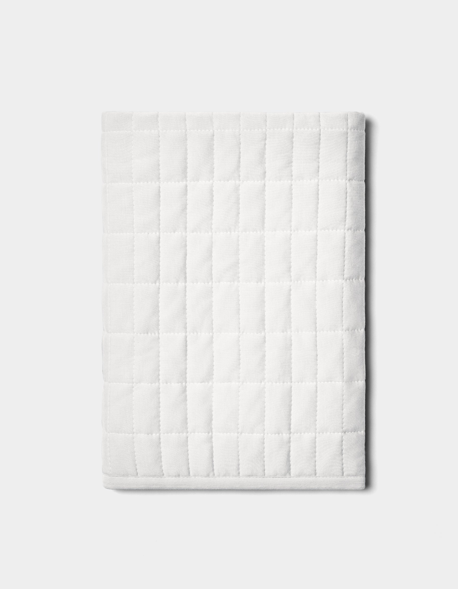The Bamboo Jersey Quilted Shams by Cozy Earth are neatly folded with a square pattern and displayed on a plain light gray background.