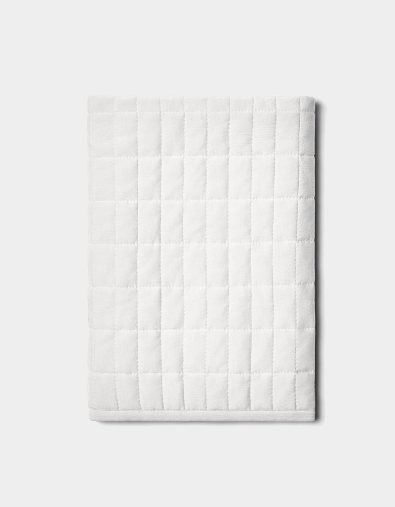 The Bamboo Jersey Quilted Shams by Cozy Earth are neatly folded with a square pattern and displayed on a plain light gray background.