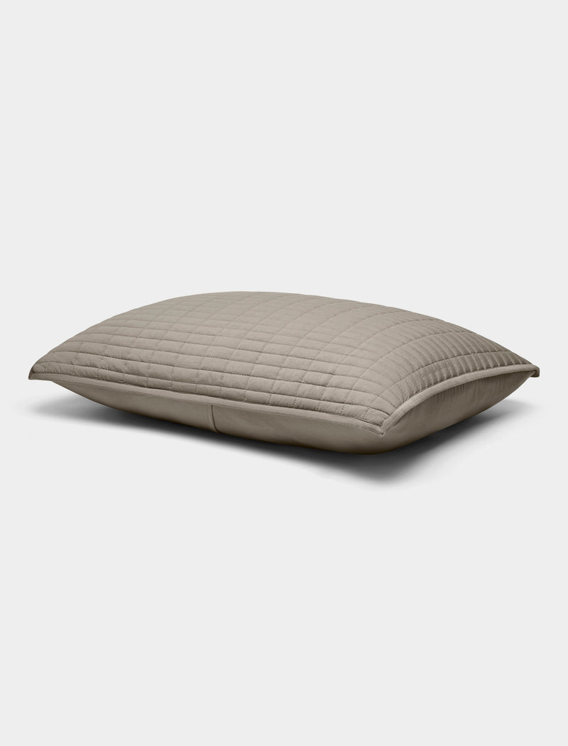 The Bamboo Jersey Quilted Shams by Cozy Earth are rectangular, light gray pillows with a quilted pattern, shown lying flat on a white background.