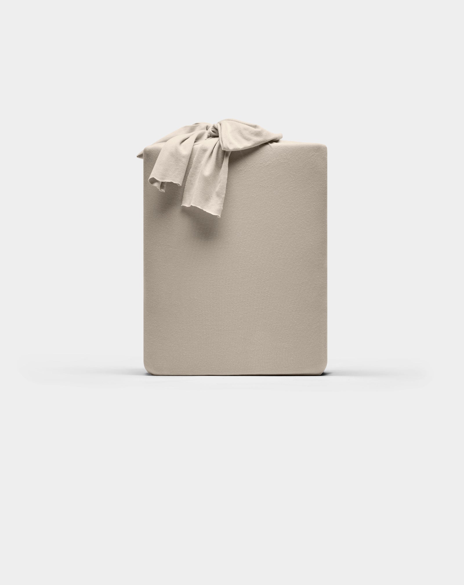 A neatly folded Cozy Earth Bamboo Jersey Sheet Set in beige, with a matching sheet draped over one corner, displayed against a plain white background.