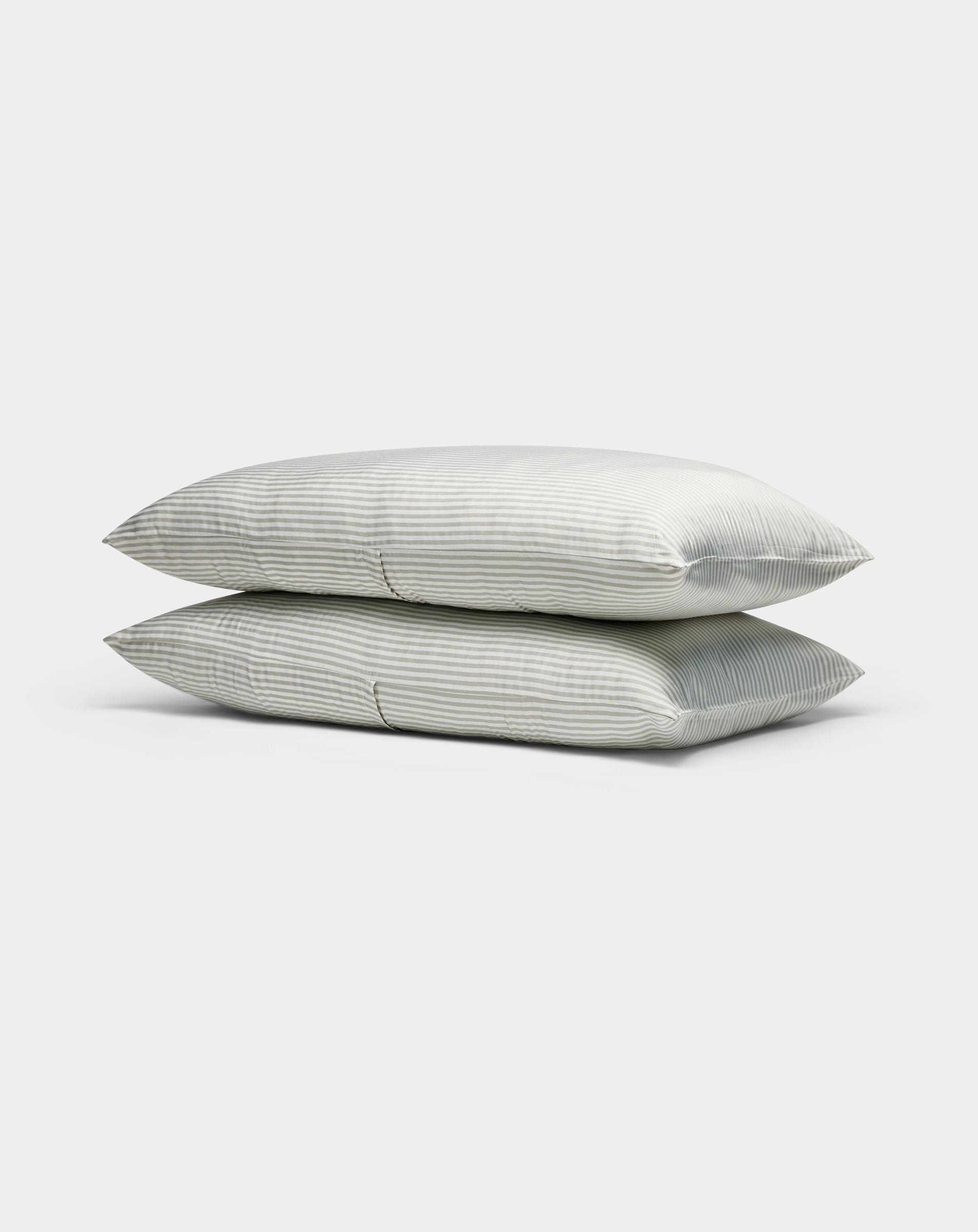 Two light gray, striped Cozy Earth Bamboo Pillowcases are stacked neatly atop each other against a plain white background.|Color:Classic Stripe in Laurel