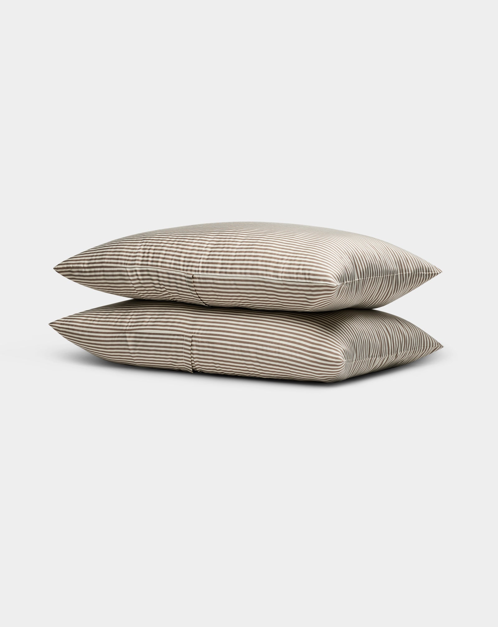 Two Cozy Earth Bamboo Pillowcases in beige, featuring thin horizontal white stripes, are stacked neatly against a plain light gray background.