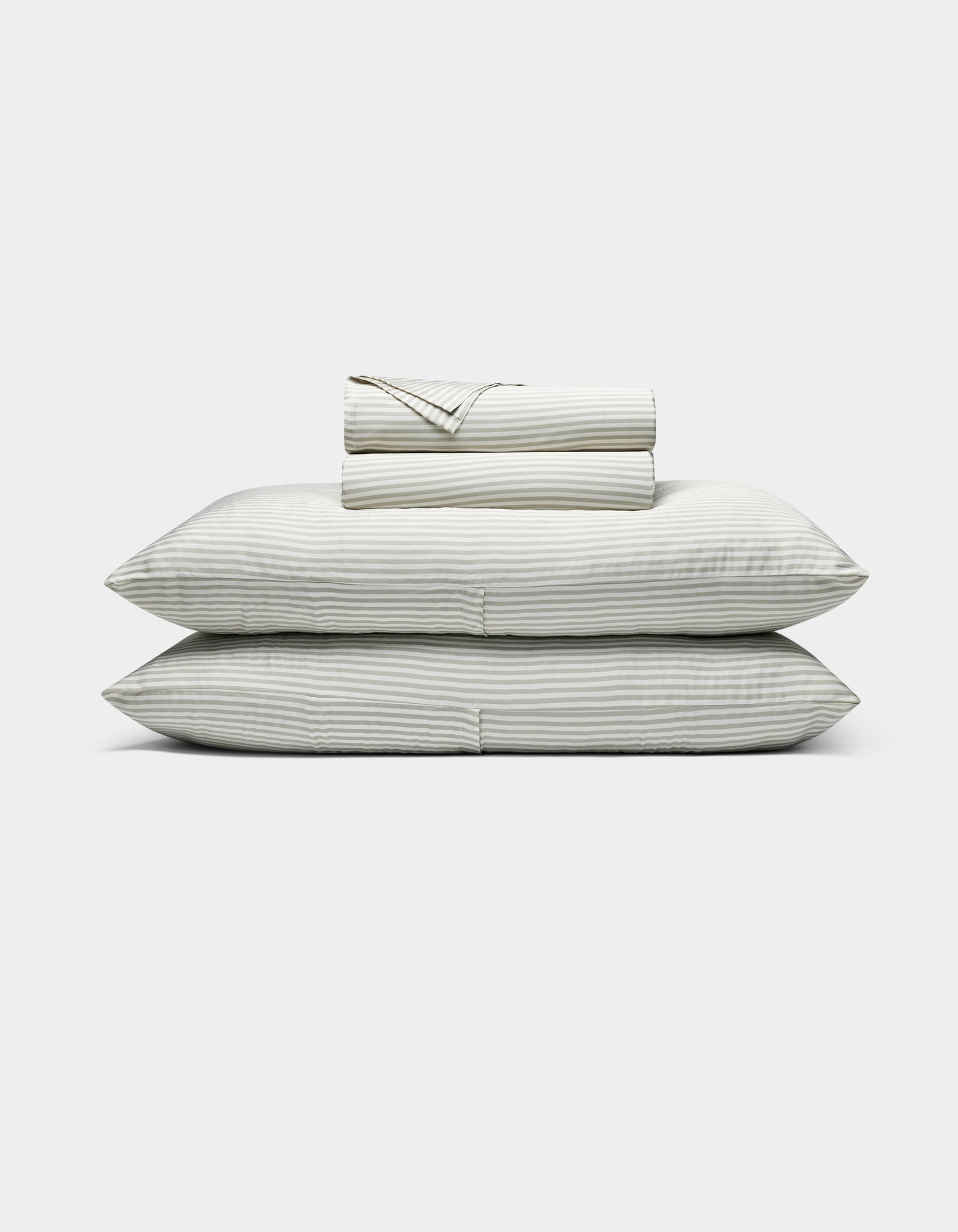 The Bamboo Sheet Set by Cozy Earth features neatly folded white sheets with subtle gray stripes, two stacked pillows, and additional folded sheets, all displayed against a plain white background.