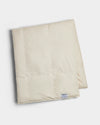 The Cozy Earth Down Alternative Throw is a folded, cream-colored quilt with a small rectangular label near the edge, displayed on a white background.|Color:Coconut