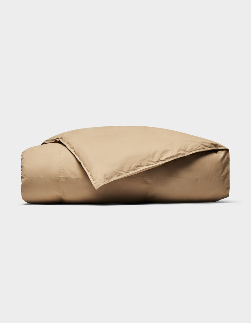 The Cozy Earth Down Alternative Throw, in tan, is neatly folded with one corner draped open against a plain white background.