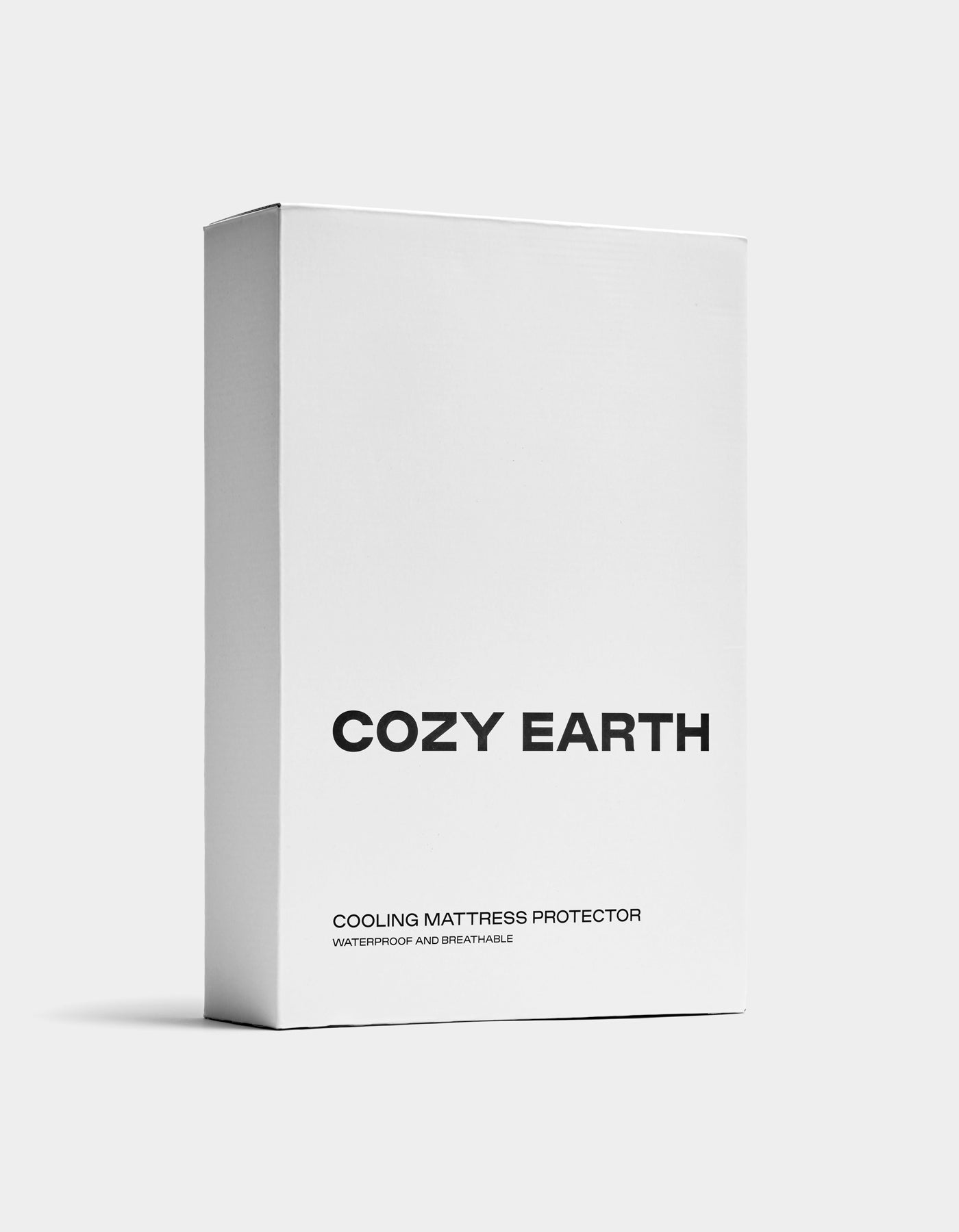 A white rectangular box labeled "Cozy Earth" in bold black letters stands upright against a light gray background, with smaller text below reading "Cooling Mattress Protector, Waterproof and Breathable.