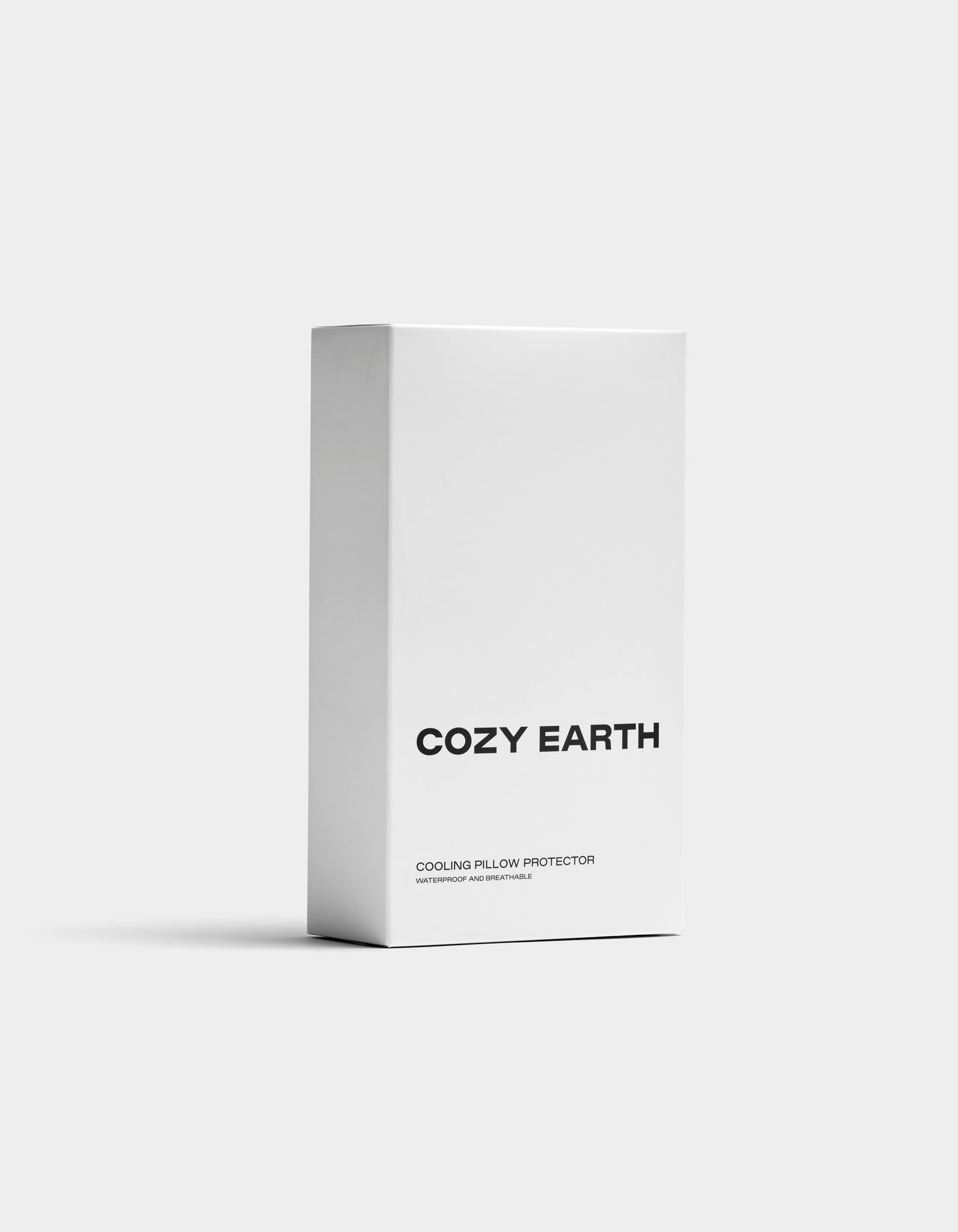 A white box with "Cozy Earth" in bold black letters and "Cooling Pillow Protector" below stands upright against a plain, light gray background.