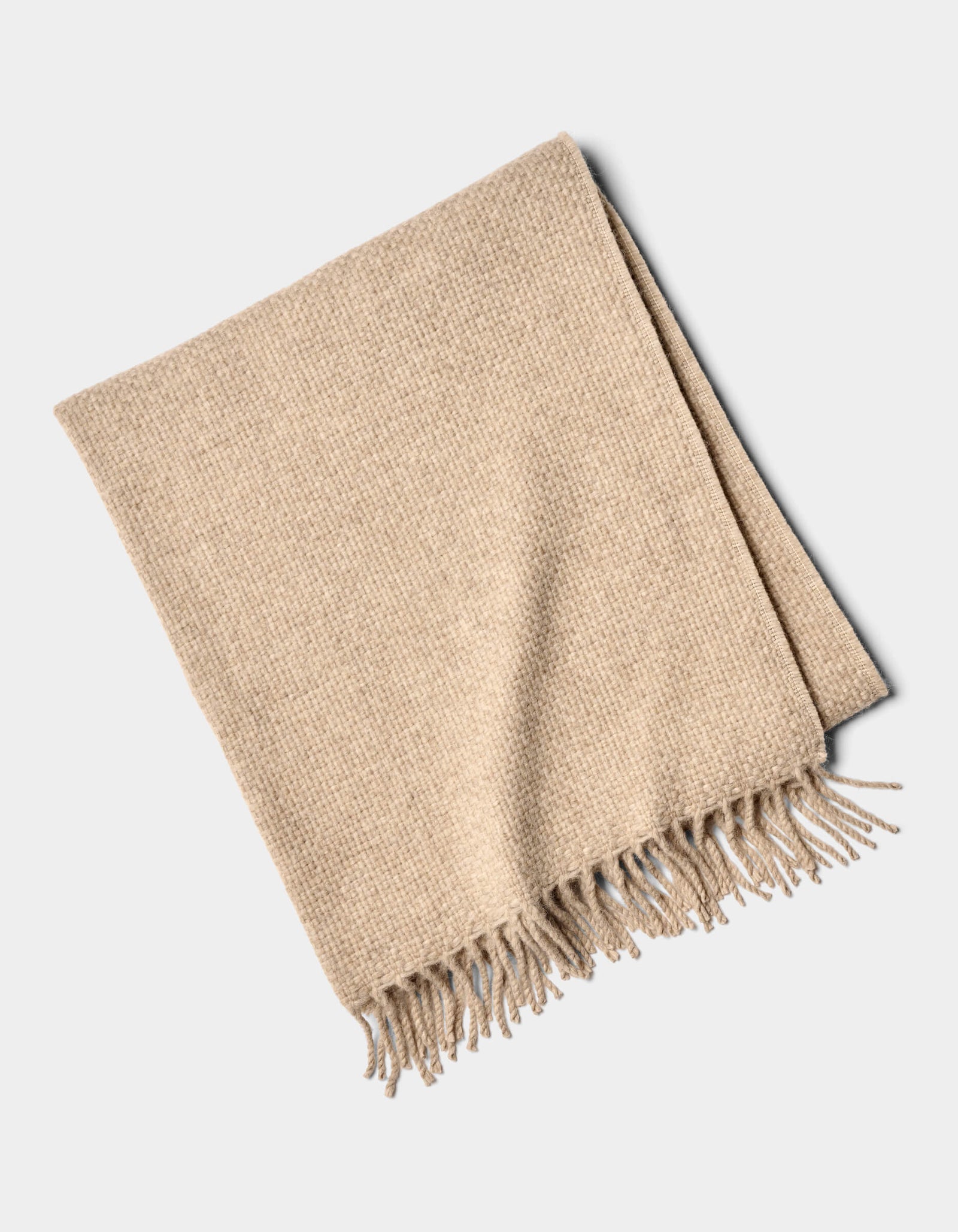 The Cozy Earth Lucia Throw is a neatly folded beige woven blanket with tasseled fringe on one edge, displayed on a plain white background.