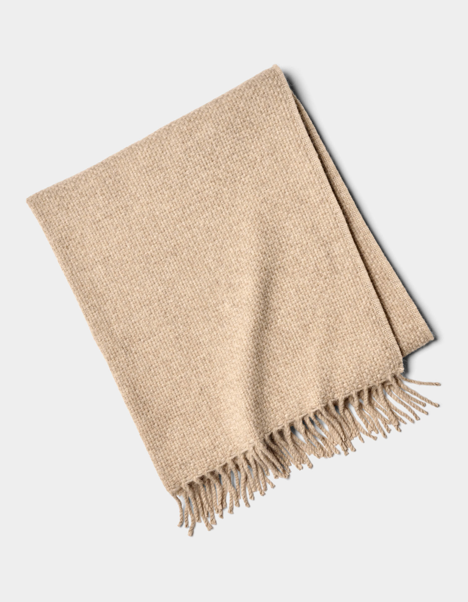 The Cozy Earth Lucia Throw is a neatly folded beige woven blanket with tasseled fringe on one edge, displayed on a plain white background.|Color:Grain