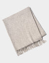 The Lucia Throw by Cozy Earth is a folded light gray woven blanket with fringe on one side, shown on a white background.|Color:Soft Grey