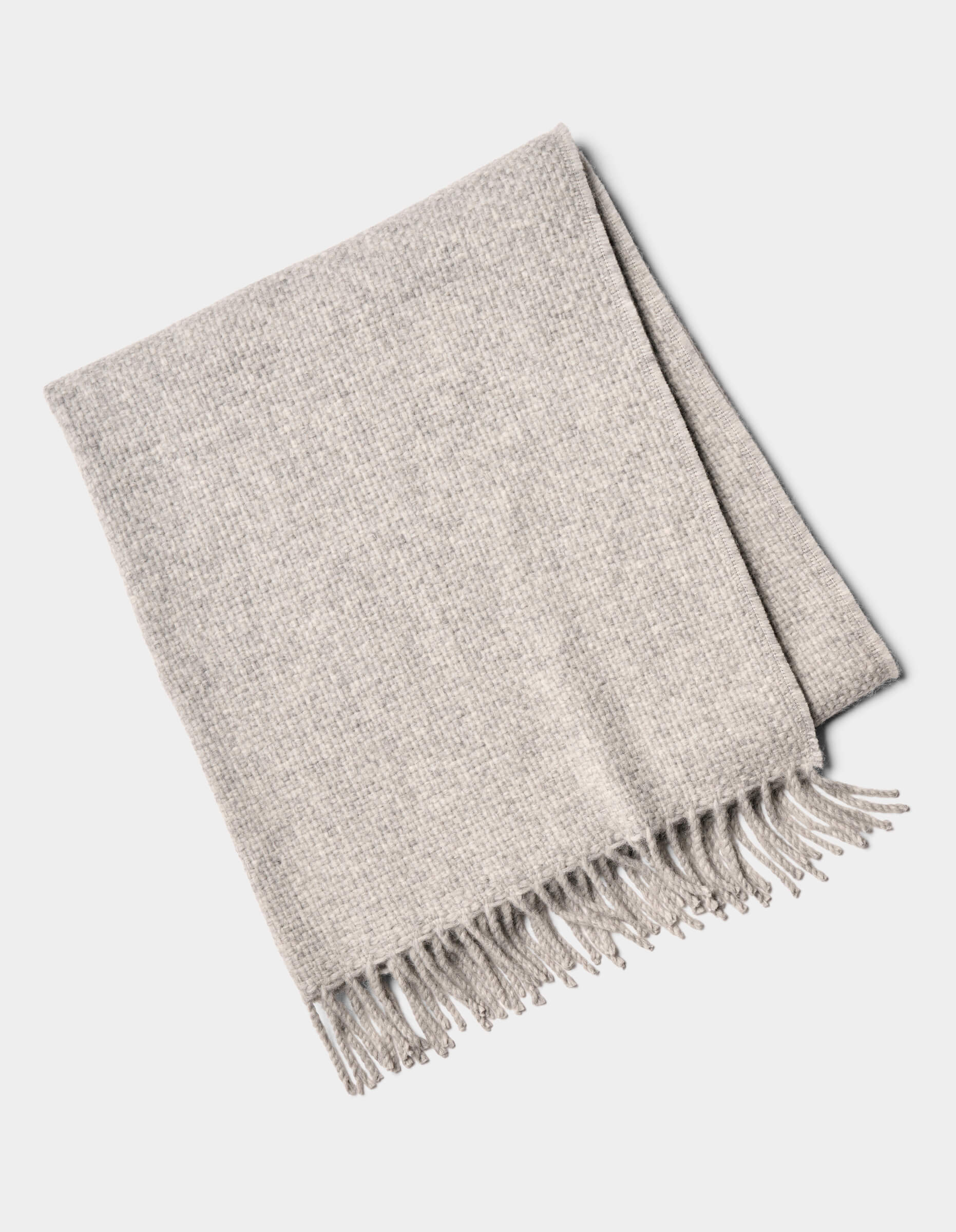 The Lucia Throw by Cozy Earth is a folded light gray woven blanket with fringe on one side, shown on a white background.|Color:Soft Grey
