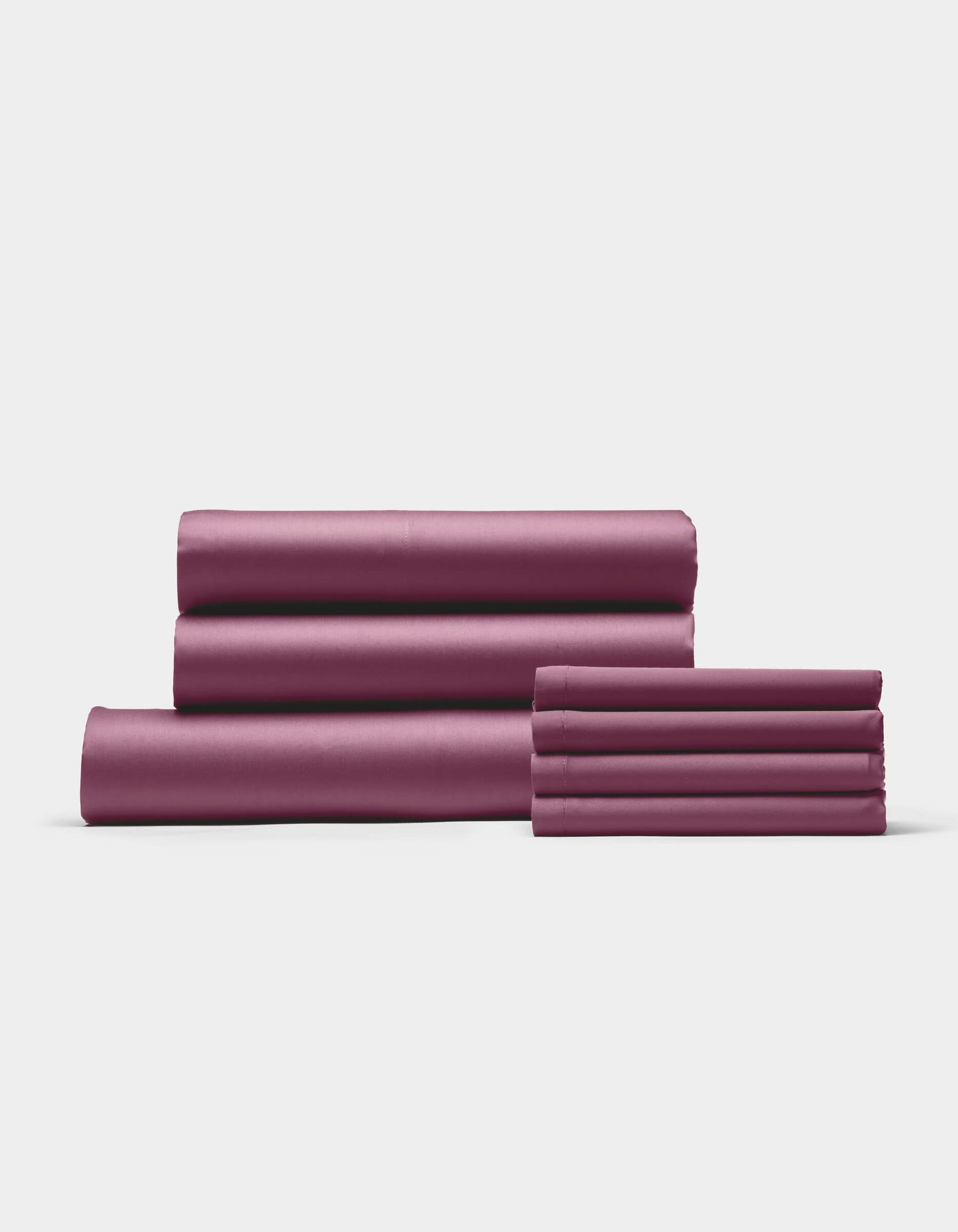 The Cozy Earth Bamboo Bedding Core Bundle features four mauve bed sheets and two matching pillowcases, neatly stacked against a plain white background.