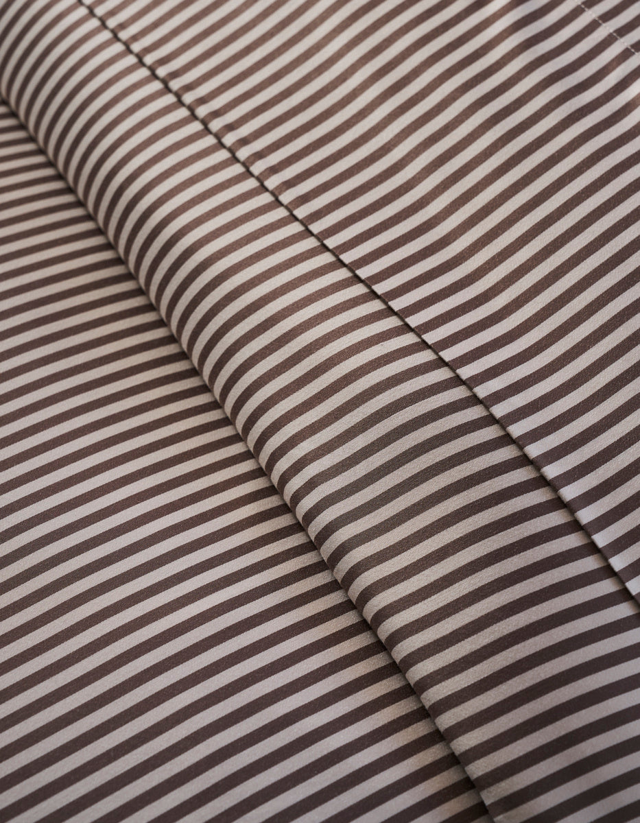 Close-up of Cozy Earth Bamboo Duvet Cover: brown and white stripes form diagonal lines, with two overlapping layers and subtle shadows at the fabric folds.