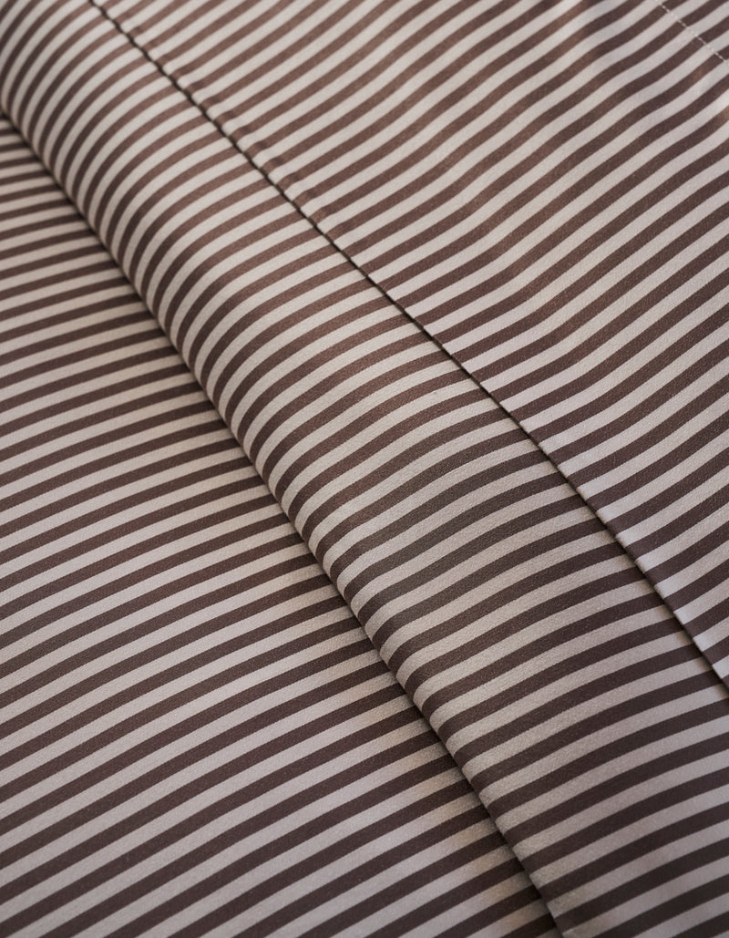 Close-up of Cozy Earth Bamboo Duvet Cover: brown and white stripes form diagonal lines, with two overlapping layers and subtle shadows at the fabric folds.