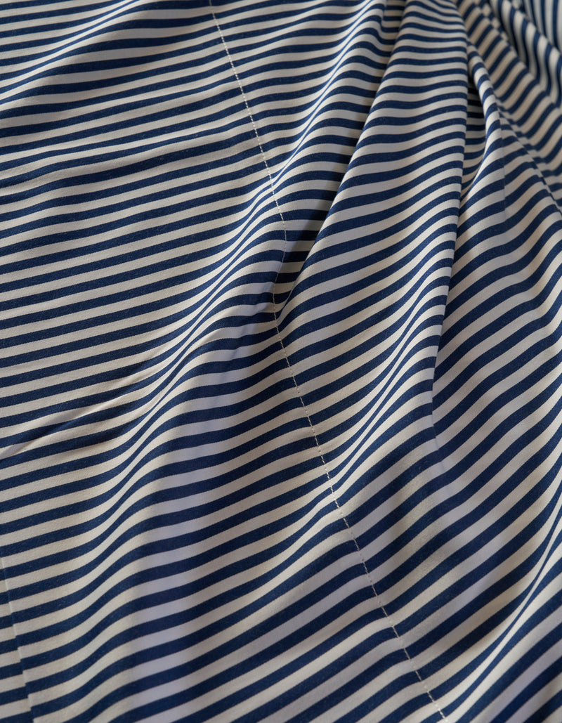 A close-up of the Cozy Earth Bamboo Duvet Cover shows thin, evenly spaced navy blue and white horizontal stripes with visible stitching and gentle folds.
