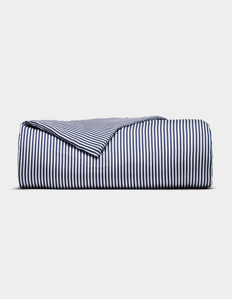 The Cozy Earth Bamboo Duvet Cover, featuring navy blue and white vertical stripes, is neatly folded and displayed against a plain light gray background.