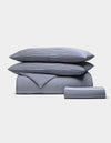 The Cozy Earth Bamboo Bedding Essential Bundle, featuring two pillows, a duvet, and a folded sheet in blue and white stripes, is neatly stacked on a plain white background.|Color:Classic Stripe in Pacific