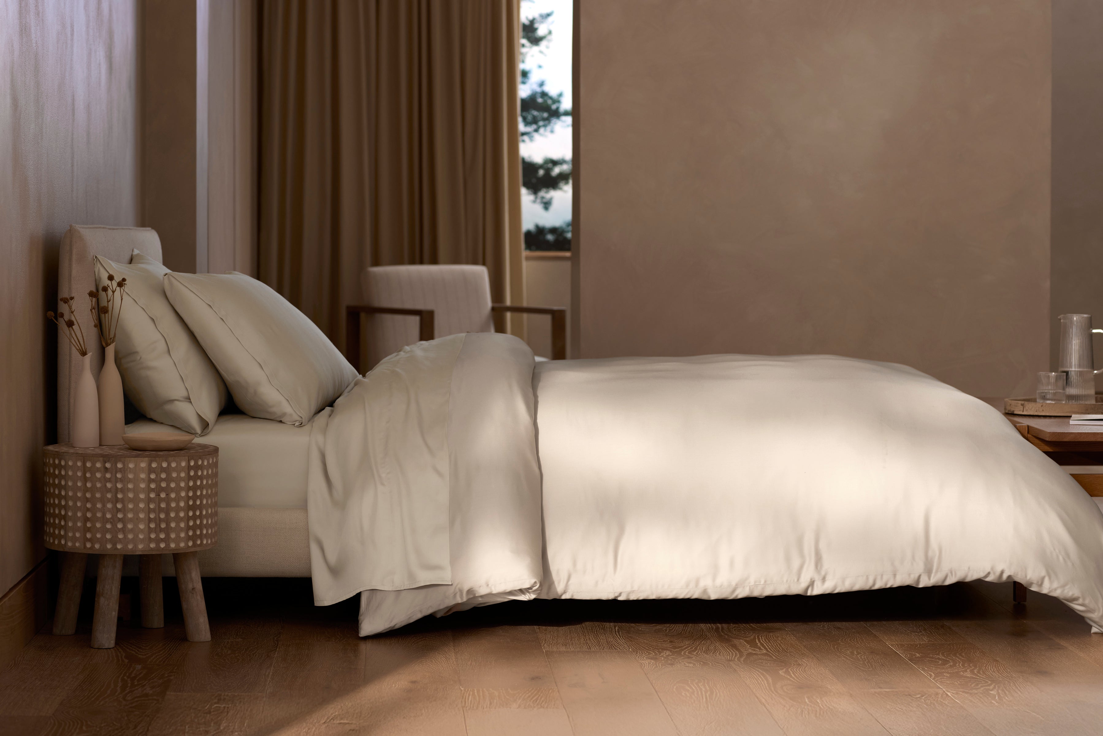 Neatly made bed with beige bedding in a bedroom setting.