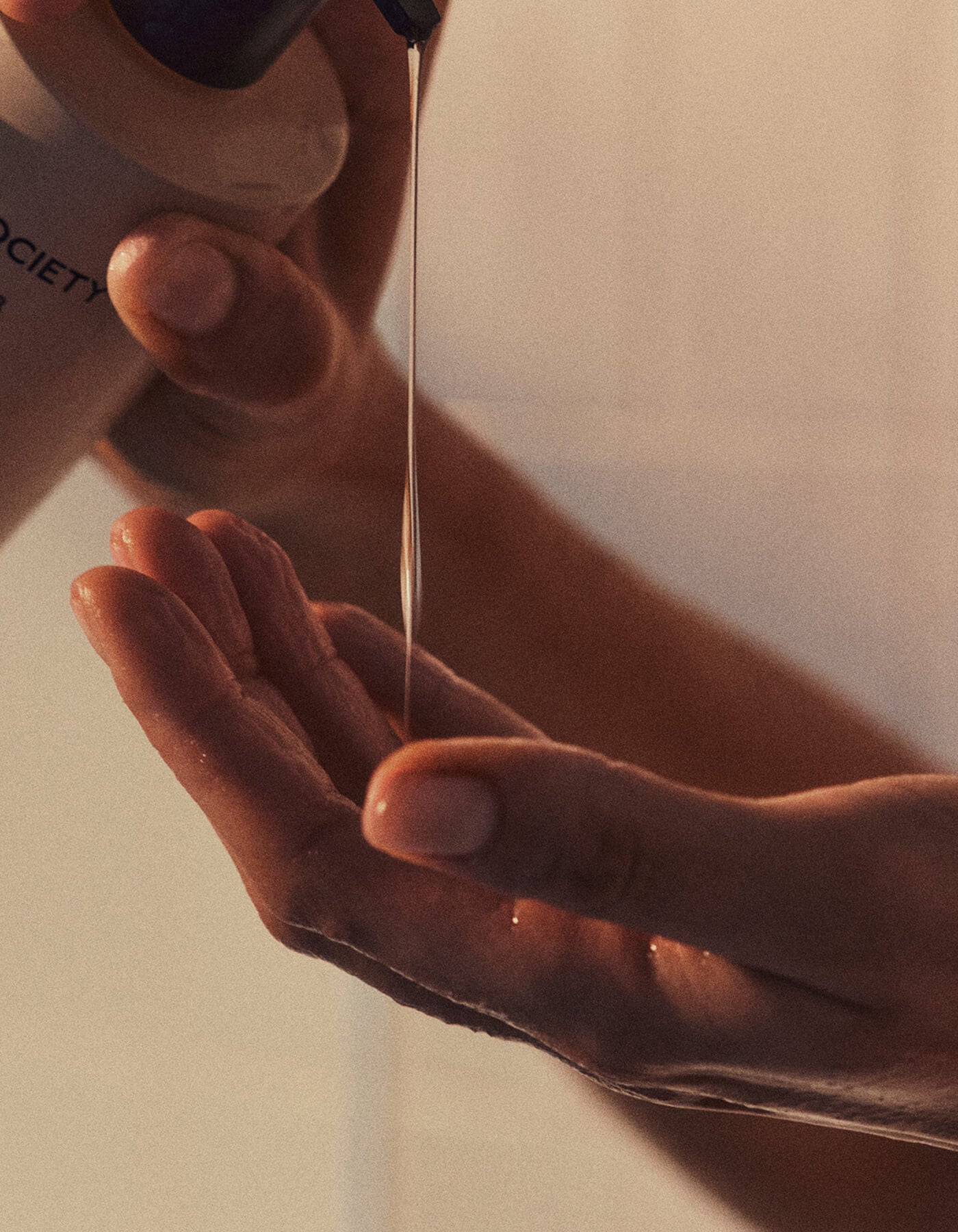 A close-up of hands pouring Cozy Earth's Fount Society Intro Kit into their palm, softly illuminated by warm light.