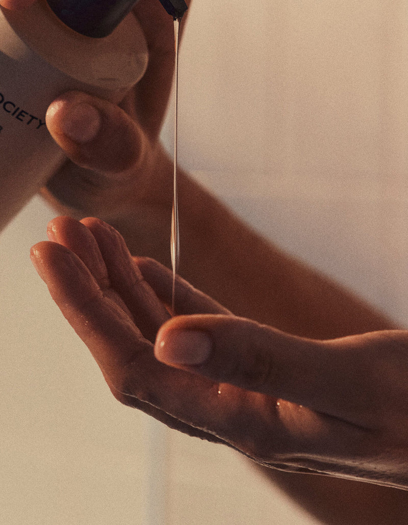 A close-up of hands pouring Cozy Earth's Fount Society Intro Kit into their palm, softly illuminated by warm light.